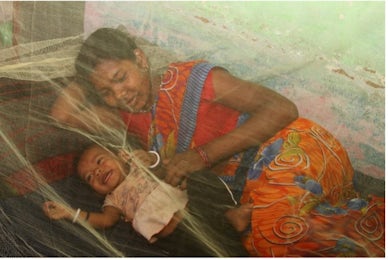 Mother and infant smiling under green bed net. Photo by Ehtisham Husain for the President's Malaria Initiative