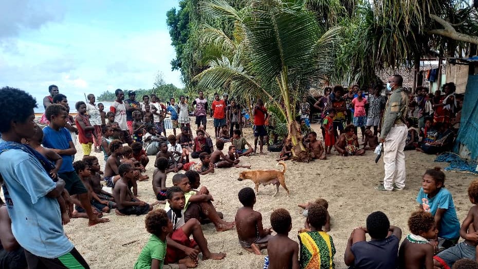Enoch Waipeli speaking to a large group of Papuans on the beach. Credit: Rotarians Against Malaria