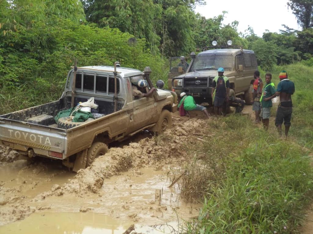 Two trucks trying to pass each other on a one-lane road but stuck in the mud t