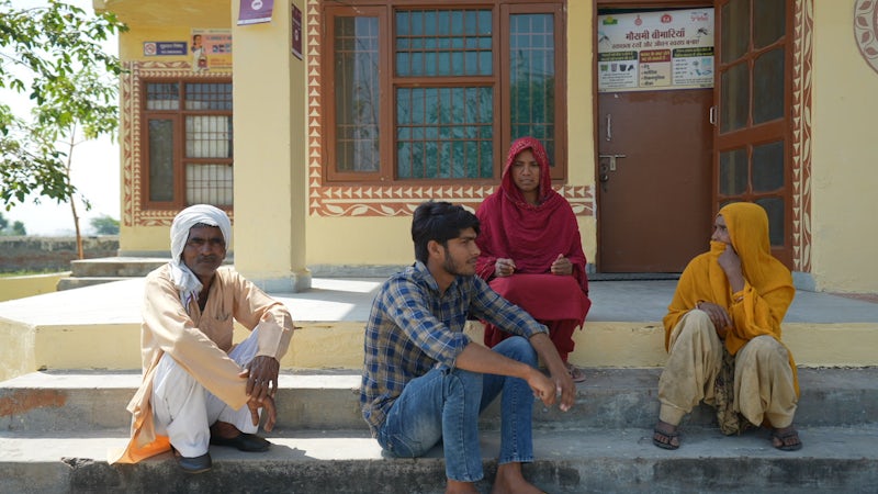 People sitting outside a local health clinic on the outskirts of New Delhi, India